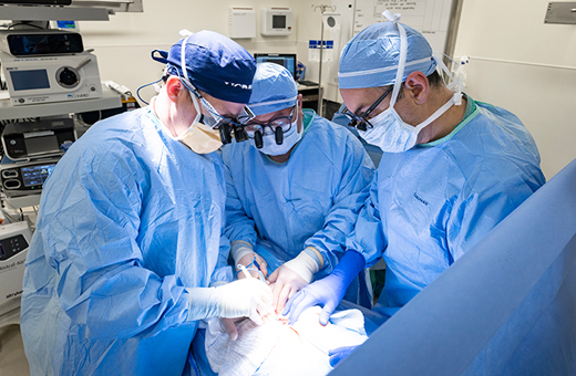 Three surgeons operating in an operating room.
