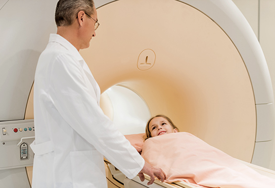 Young girl going into MRI machine smiling at her doctor.