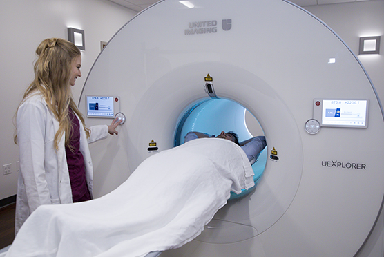Female radiologist putting patient into PET scan machine