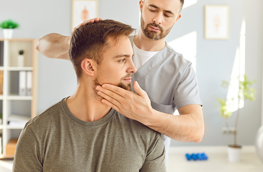 A physical therapist turns a patient's head to one side.