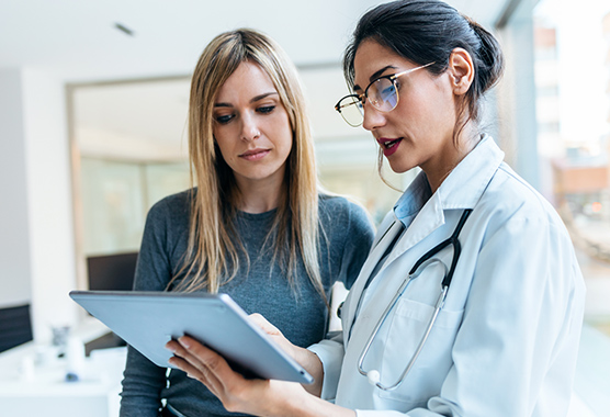 Female patient looking at tablet with health care provider preparing for plastic and reconstructive surgery. 