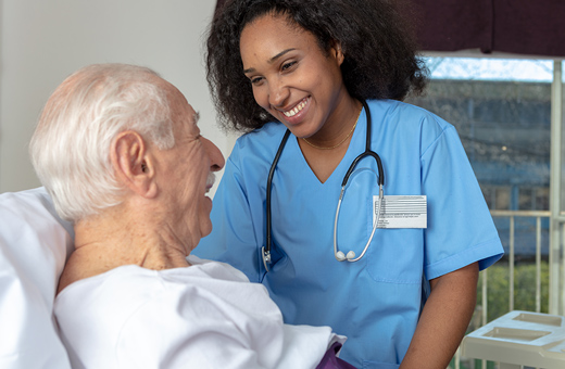 Health care provider caring for man in hospital bed after shoulder replacement.