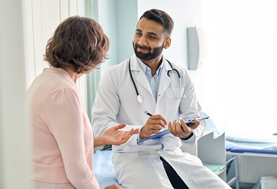 A woman speaking to a doctor who is taking notes.