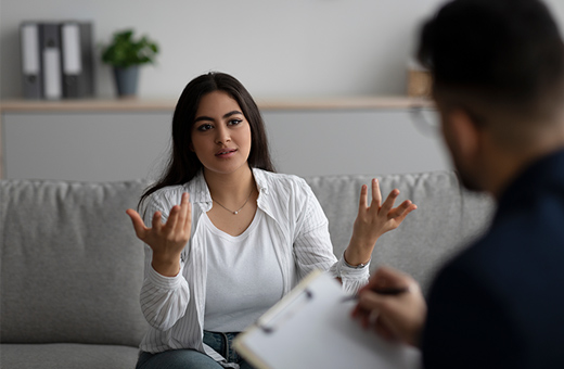 A woman speaks to a man taking notes.