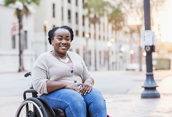 A young woman in a wheelchair smiles at the camera.