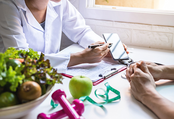 Registered dietitian talking to a person about nutrition sitting at a table with fruit and set of hand weights.