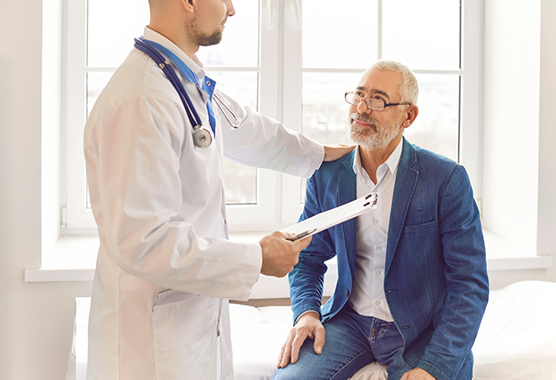 A doctor speaks to an older male patient about urologic surgery.