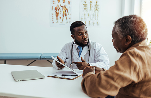 A male doctor and patient look at a tablet and discuss urostomy surgery.