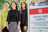3 women in front of a smoke-free campus sign