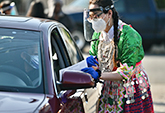 UC Davis undergraduate student Zoua Vang, in traditional Hmong clothing, administers flu screening questionnaire to motorist