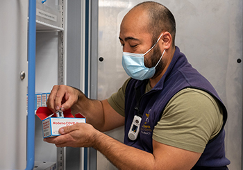 Pharmacy technician Joel Miyake checks on boxes of the Moderna COVID-19 vaccine at the UC Davis Medical Center.
