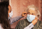 Caregiver putting mask on older adult