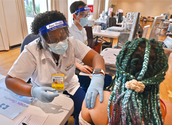 Nursing student Judy Njuguna-Hamilton administers COVID-19 vaccine for UC Davis Health patients.