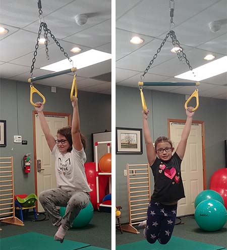 10-year-old girls hanging from rings inside a therapy room