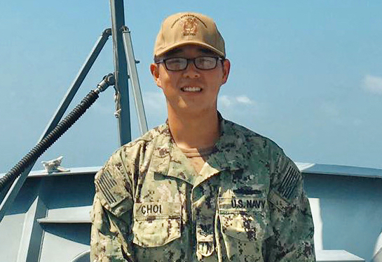 Sailor Justin Choi displays the commemorative paddle awarded to him at the conclusion of his enlistment in the U.S. Navy