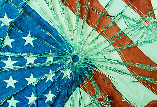 Portion of an American flag behind glass with a bullet hole