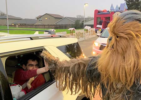21-year-old boy leans out of a car window to hi-five someone dressed as Chewbacca.