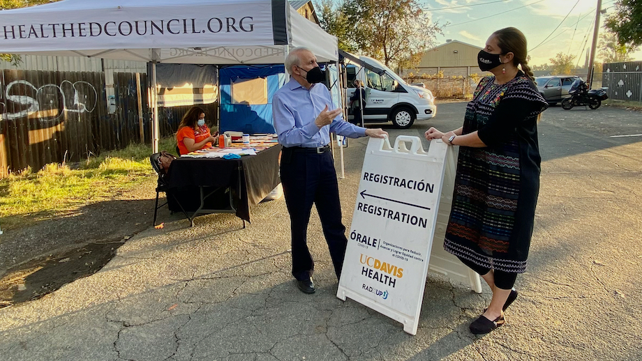 Sergio Aguilar-Gaxiola of UC Davis Health and Esmeralda Garza of Yolo County talk in front of an ÓRALE sign in Knights Landing