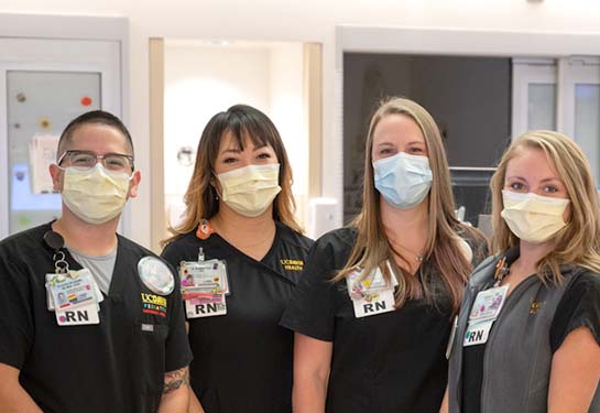 Four nurses standing in the emergency department wearing scrubs and masks