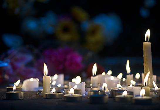 candles flicker outside at night in a makeshift memorial