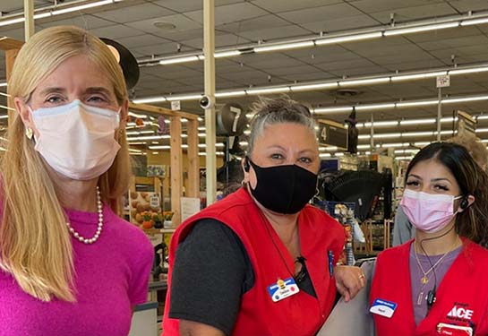 Three people in masks pose at the register at Emigh Ace Hardware in Sacramento.