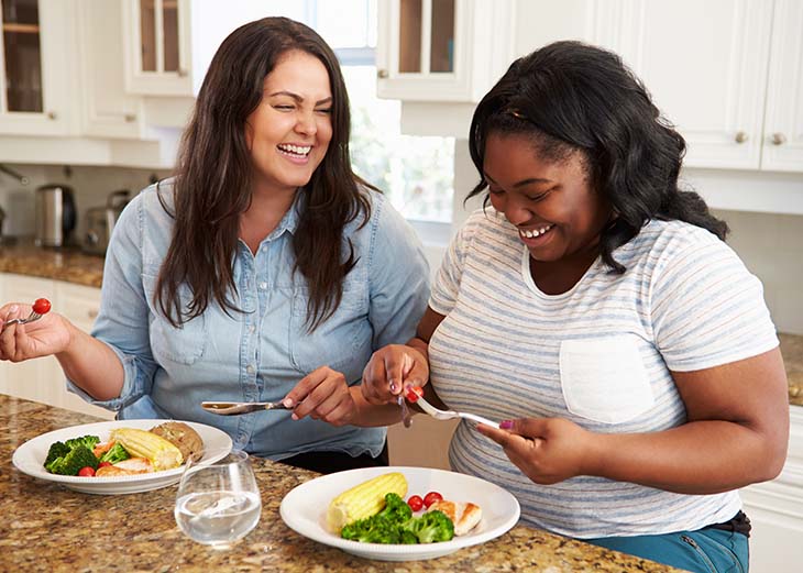 two overweight women eating healthy meal in kitchen