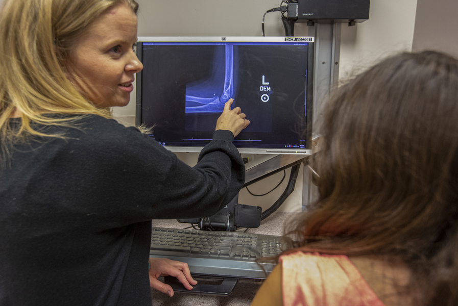 Doctor pointing at x-ray on computer screen to patient looking at screen