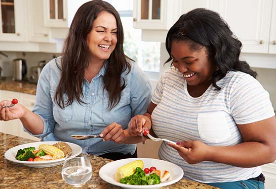 two overweight women eating healthy meal in kitchen
