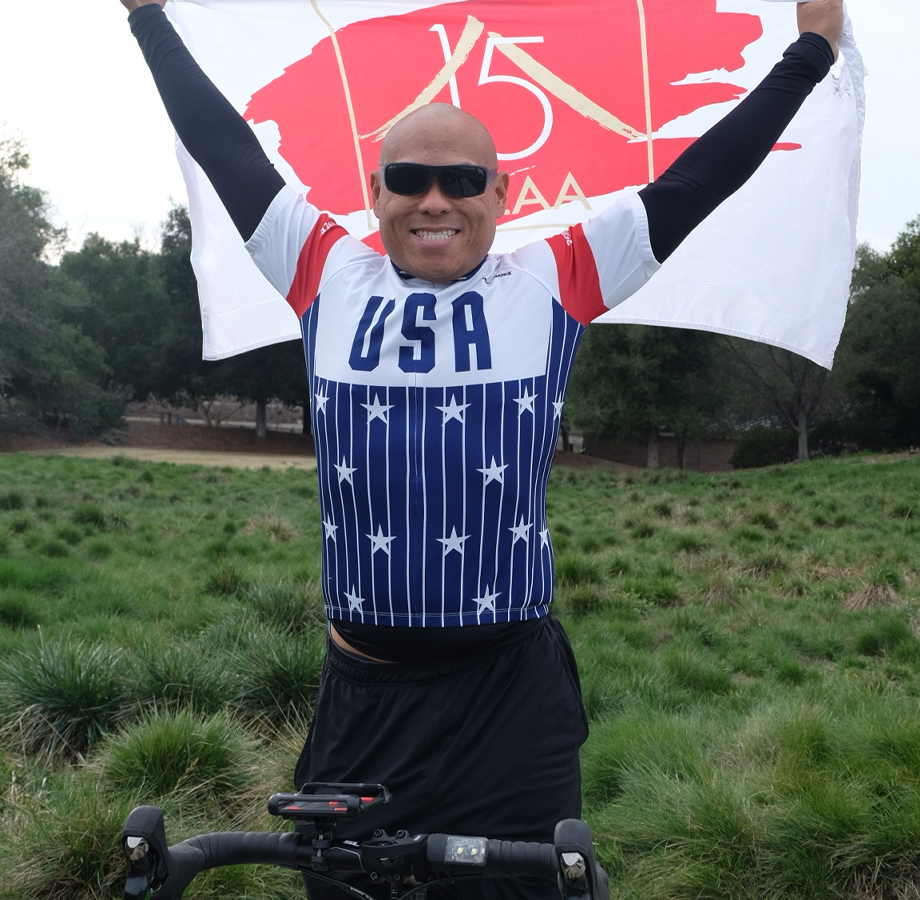 Wilson Du holding victory flag overhead while on his bike