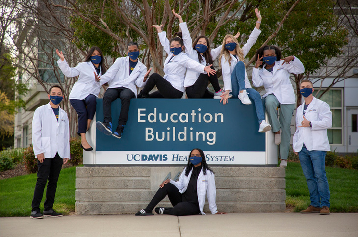 Medical students smiling and waving arms on sign