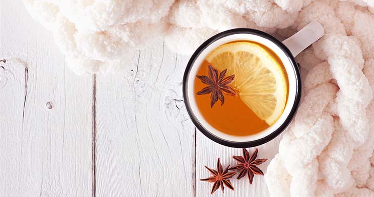 Lemon spice tea, top view on a white wood background with blanket.