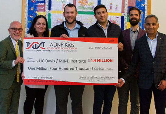 A group of five people holds a large plastic check for $1.4 million dollars for a UC Davis MIND Institute research program. 