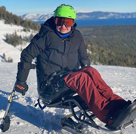 Bassem Mansour sitting on monoski on a mountain covered in snow