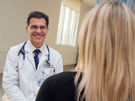 Doctor Martin Cadeiras wearing a white coat speaking with a patient 