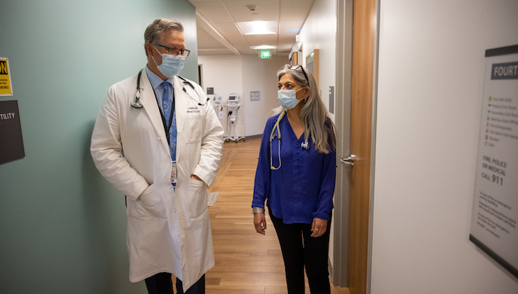 Two physicians are seen talking together in a medical clinic