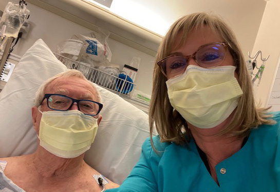 Art Foster, who recovered from a serious illness, lays in hospital bed with nurse beside him