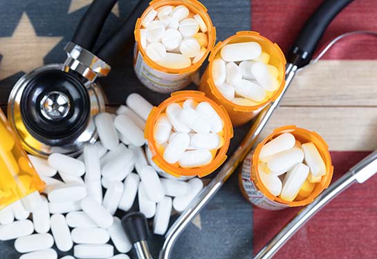 Top view of full prescription bottles with stethoscope and pills on rustic wooden United States background
