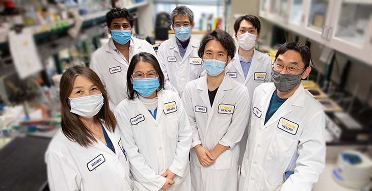 Seven researchers wearing lab coats at Izumiya Lab
