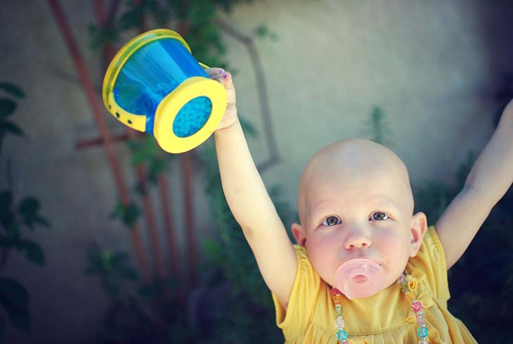 Female baby holding cup in the air