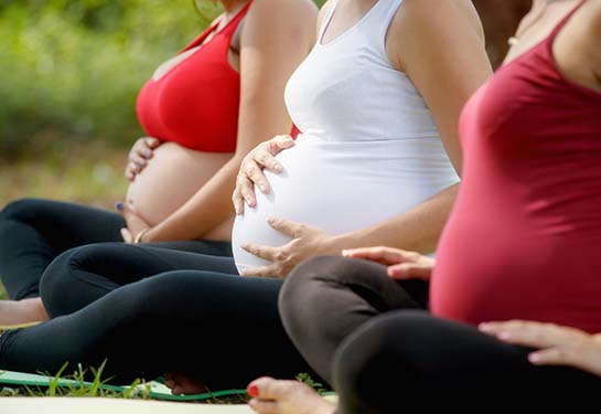 Pregnant women, group of moms during pregnancy attending prenatal lesson in city park. The girls massage their belly.