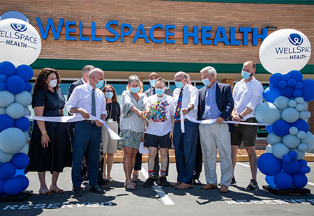 A group of people including UC Davis School of Medicine Interim Dean Susan Murin stand before WellSpace Health sign 