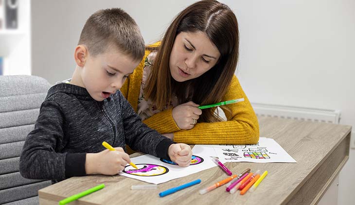 Five years old boy drawing at his educator's office