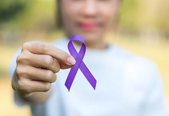 Woman holding purple ribbon representing Alzheimer’s and Brain Awareness Month in June. 
