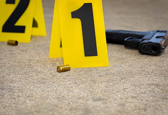 Gun shell casing, yellow evidence tags and a gun at crime scene.