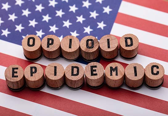 Elevated view of Opioid Epidemic text on wooden cork over American flag