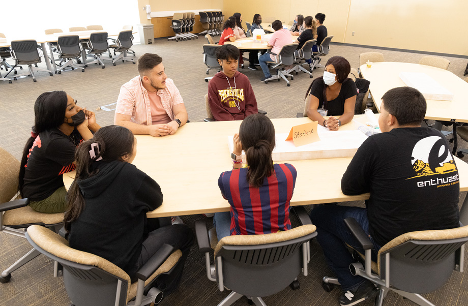  A group of students sit around a table in discussion