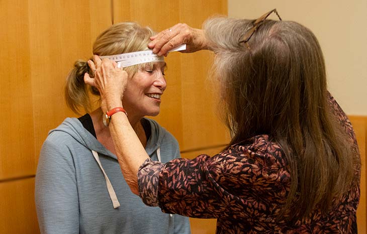 A doctor uses a measuring tape to measure a woman’s head circumference during a research visit at the MIND Institute. 