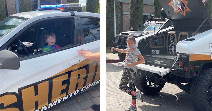 On the left is a young boy with Down syndrome sits in the driver’s seat of a police car on the right a young girl leans against a Sheriff’s vehicle, posing for a photo. 