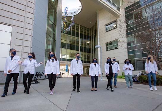 Students walking while wearing a mask and white coats