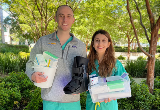 Medical students Carter White and Aida Nasirishargh display an orthopedic boot and other surplus items they collect and donate